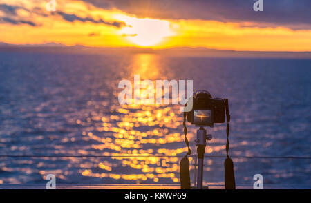 Coucher de soleil sur l'eau et un appareil photo DSLR Banque D'Images