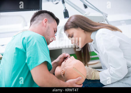 Des prothèses dentaires, l'hygiène buccale. Les mains de la prothétique tout en travaillant sur le dentier, fausses dents, une étude et une table avec des outils de dentiste. Banque D'Images