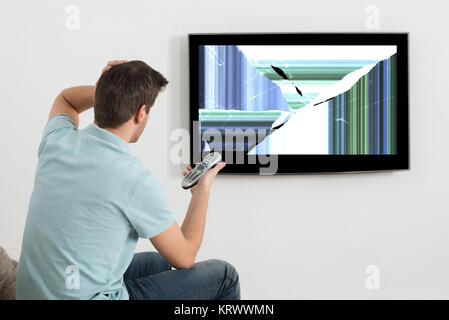 Homme assis sur le canapé en face de la télévision Banque D'Images