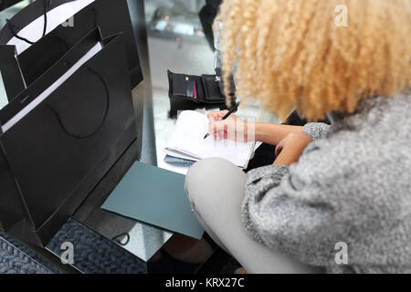 La femme écrit dans un ordinateur portable. girl prendre des notes tout en étant assis sur le canapé Banque D'Images