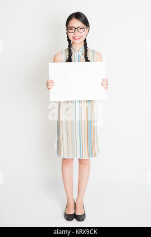 Oriental girl holding white paper card Banque D'Images