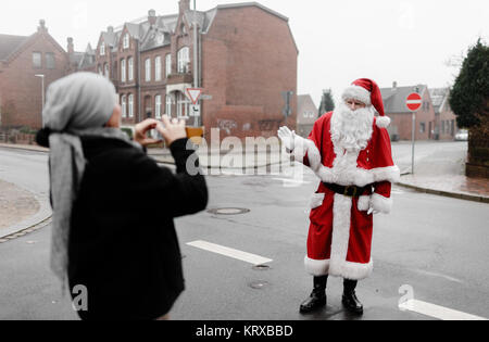 Theo Lorenzen, le seul Père Noël dans le Schleswig-Holstein, selon lui, se dresse avec le 'Code d'honneur - Sceau de qualité" sur une rue et permet aux gens de prendre des photos de lui à Husum, Allemagne, 20 décembre 2017. Photo : Markus Scholz/dpa Banque D'Images