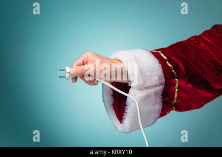 Part du Père Noël tenant une prise électrique sur fond bleu Banque D'Images