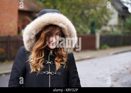 Young woman wearing hooded pelage d'hiver, jouer coy Banque D'Images