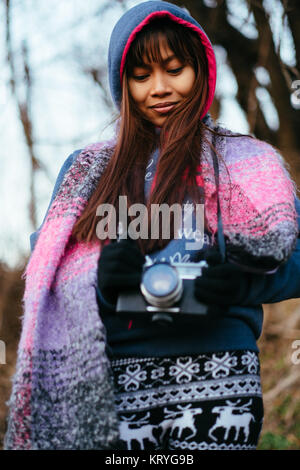 Girl in winter coat holding camera Banque D'Images