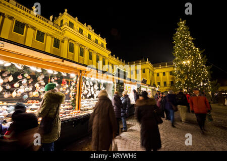 Marché de Noel lumineux avec le palais de Schönbrunn et fairy lights decorated Christmas Tree, au crépuscule, les touristes et les gens en fête Banque D'Images