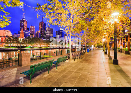 La demande pour des clients sur la rivière Yarra Southbank Melbourne CBD en latéral au lever du soleil sous les arbres feuillus et allumé les lampes de rue. Banque D'Images