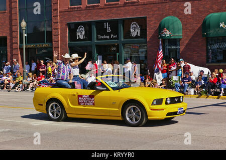 Cody, Wyoming, USA - Juillet 4th, 2009 - alors secrétaire d'état du Wyoming Max Maxfield avec son épouse Gayla Maxfield équitation dans une décapotable et agitant whi Banque D'Images