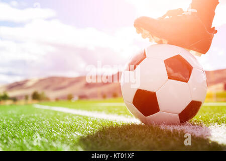 Ballon de soccer player avec le pied sur le terrain de football Banque D'Images