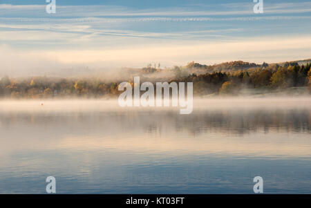 La brume s'élève de ses eaux calmes du lac Windermere, à Ambleside, à côté de l'automne en Angleterre woodland's Lake District National Park. Banque D'Images