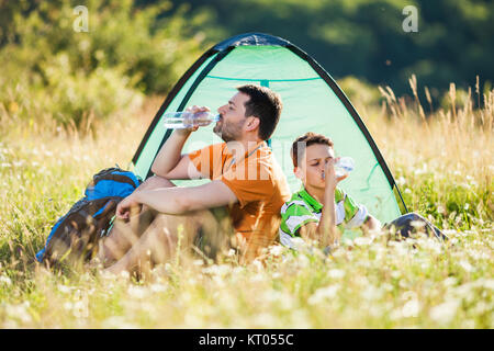 Père et fils sont en camping dans la nature. Ils sont l'eau potable. Banque D'Images