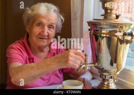 Femme âgée de boire du thé à table. Samovar Russe classique. Banque D'Images