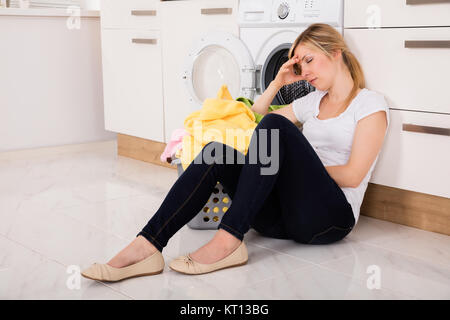 Épuisé Femme assise près d'un lave-linge Banque D'Images