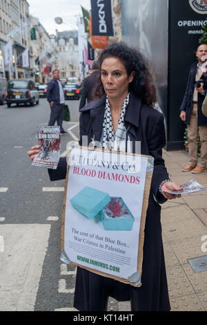 Une femme tenant une affiche 'Tiffany & Co. les fournisseurs de diamants du sang" des tracts à Londres protester contre la vente de "diamants du sang" du groupe Steinmetz qui a financé l'armée israélienne de la Brigade Givati, accusé de crimes de guerre. Banque D'Images