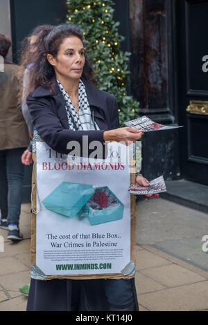 Une femme tenant une affiche 'Tiffany & Co. les fournisseurs de diamants du sang" des tracts à Londres protester contre la vente de "diamants du sang" du groupe Steinmetz qui a financé l'armée israélienne de la Brigade Givati, accusé de crimes de guerre. Banque D'Images