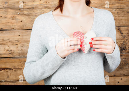 Concept d'amour - Girl holding textile un cœur rouge dans ses mains en face de coeur Banque D'Images