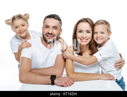 Smiling family en blanc T-shirts hugging Banque D'Images