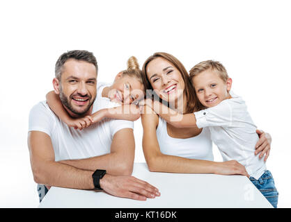 Smiling family en blanc T-shirts hugging Banque D'Images