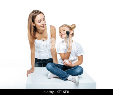 Mère regardant fille avec brosse de maquillage Banque D'Images