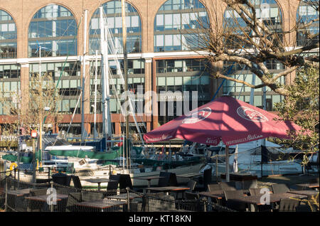 Zizzi Restaurant italien avec parapluie tables vides à St Katharine Dock avec des bateaux et les locaux à bureaux Londres Angleterre Royaume-Uni UK Banque D'Images