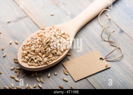 Heap de l'épeautre en cuillère en bois sur la table avec une étiquette de texte. Banque D'Images