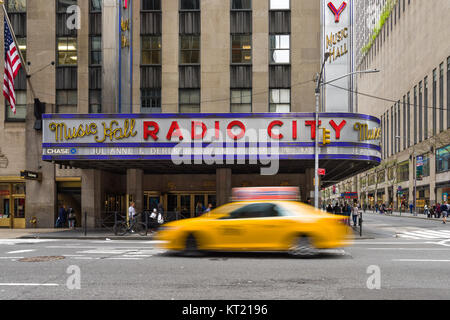 Un taxi jaune durs passé le Radio City Music Hall building sur la 6ème Avenue à Manhattan, New York, USA Banque D'Images