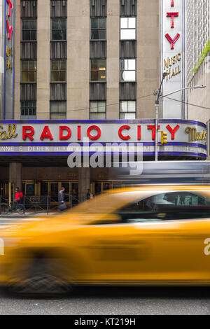 Un taxi jaune durs passé le Radio City Music Hall building sur la 6ème Avenue à Manhattan, New York, USA Banque D'Images