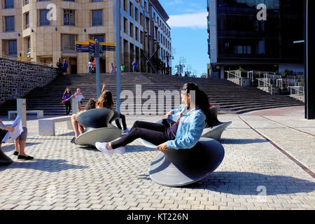 Les femmes tournent autour sur des chaises à l'extérieur de la filature wobbly Zeitz Mocaa art museum à Cape Town, Afrique du Sud Banque D'Images