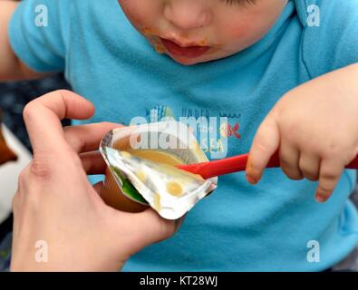 Bébé garçon à l'aide d'une cuillère pour manger un dessert Banque D'Images