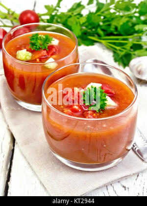 Tomate soupe dans deux verres de persil sur nappes Banque D'Images