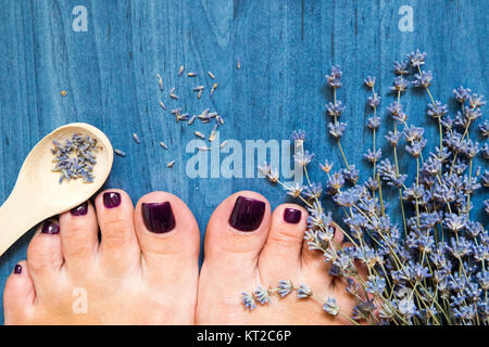 Photo Gros plan d'une femme avec les pieds sur les ongles des pieds et de la lavande. Au spa beauté. Concept de soins des jambes Banque D'Images