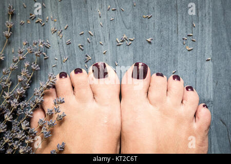 Photo Gros plan d'une femme avec les pieds sur les ongles des pieds et de la lavande. Au spa beauté. Concept de soins des jambes Banque D'Images