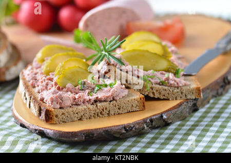 Pain de campagne avec saucisson sur une tranche de bois rustique Banque D'Images