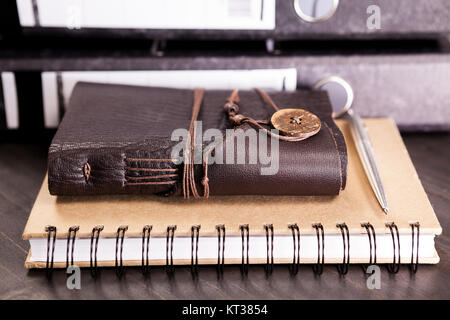 Couvert de cuir vintage retro notebook à côté d'une pile de dossiers sur une table Banque D'Images