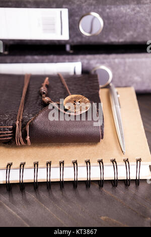 Couvert de cuir vintage retro notebook à côté d'une pile de dossiers sur une table Banque D'Images