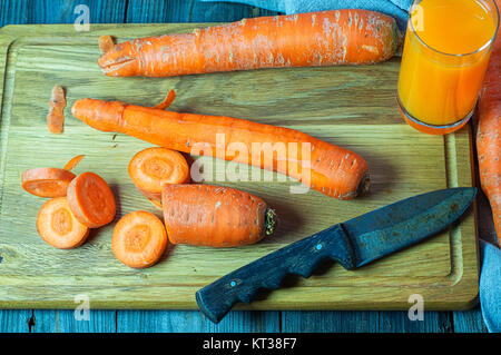 Carottes fraîches sur la planche à découper pour le jus de carotte Banque D'Images