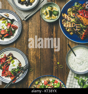 Télévision à jeter de souper santé table. Salade fraîche, légumes grillés avec du yogourt et sauce à l'aneth, olives marinées, de l'eau citronnée sur des backgrou Banque D'Images