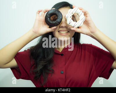 Asian woman holding donut sur fond blanc, chemise rouge, de longs cheveux noirs Banque D'Images