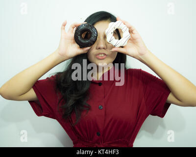 Asian woman holding donut sur fond blanc, chemise rouge, de longs cheveux noirs Banque D'Images