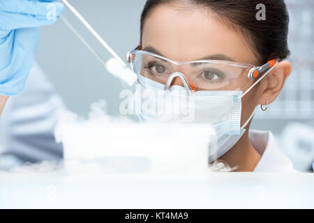 Jeune femme scientifique dans des lunettes et fabrication de masques experiment in laboratory Banque D'Images