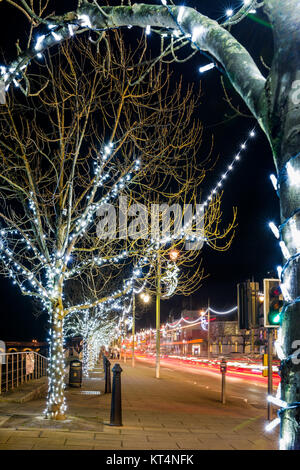 Les lumières de Noël illuminent le quai à Bideford au coucher du soleil après un temps couvert mais doux dans le nord du Devon. Banque D'Images