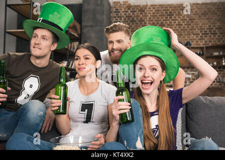 Heureux les jeunes amis de boire la bière verte chapeaux et célébrer St Patricks day Banque D'Images