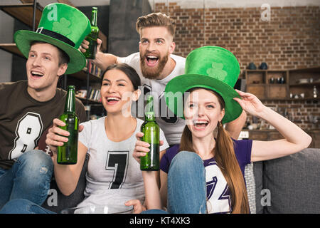 Heureux les jeunes amis de chapeaux verts de boire une bière et de célébrer St Patricks day Banque D'Images