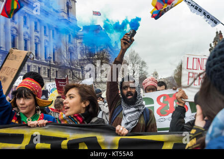 Un homme dans le bloc de première ligne mondiale détient une fumée bleue flare comme ils descendent Whitehall passé le ministère des Affaires étrangères et du Commonwealth sur le climat de Mars et emploi à Londres. Banque D'Images