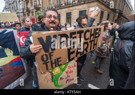 Un homme dans la première ligne de bloc à l'avant de la carie Climat Mars à Londres une grande affiche "damnés de la Terre' et une plus petite en espagnol contre les mines d'Amérique du Sud.. Banque D'Images