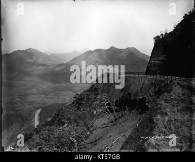 Cette photographie de Brother Bertram capture New Pali Road, une route panoramique à Hawaï. L’image met en valeur la beauté naturelle du paysage, avec une végétation luxuriante et une vue imprenable sur le terrain de l’île. Banque D'Images