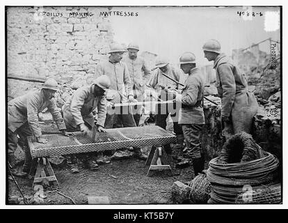 Cette photographie représente des soldats français (Poilus) pendant la première Guerre mondiale, fabriquant des matelas, soulignant les luttes quotidiennes des soldats dans les tranchées. Banque D'Images