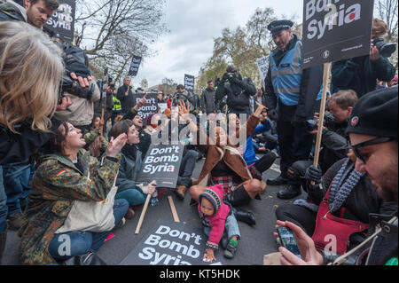 Ne pas bombarder la Syrie les manifestants s'asseoir sur la route et de bloquer les demandes de police ignorant Whitehall descendre la route. Banque D'Images