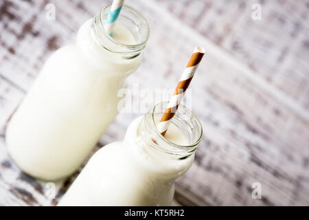 Deux bouteilles de lait avec des pailles à rayures debout sur ancienne table. Banque D'Images