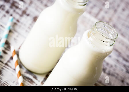 Deux bouteilles de lait avec des pailles à rayures debout sur ancienne table. Banque D'Images